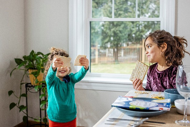 Two children smile while holding and eating matzah